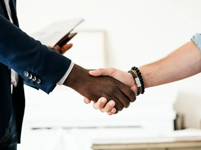 Close-up of two people shaking hands in office setting symbolizing trust, cooperation, and successful deal